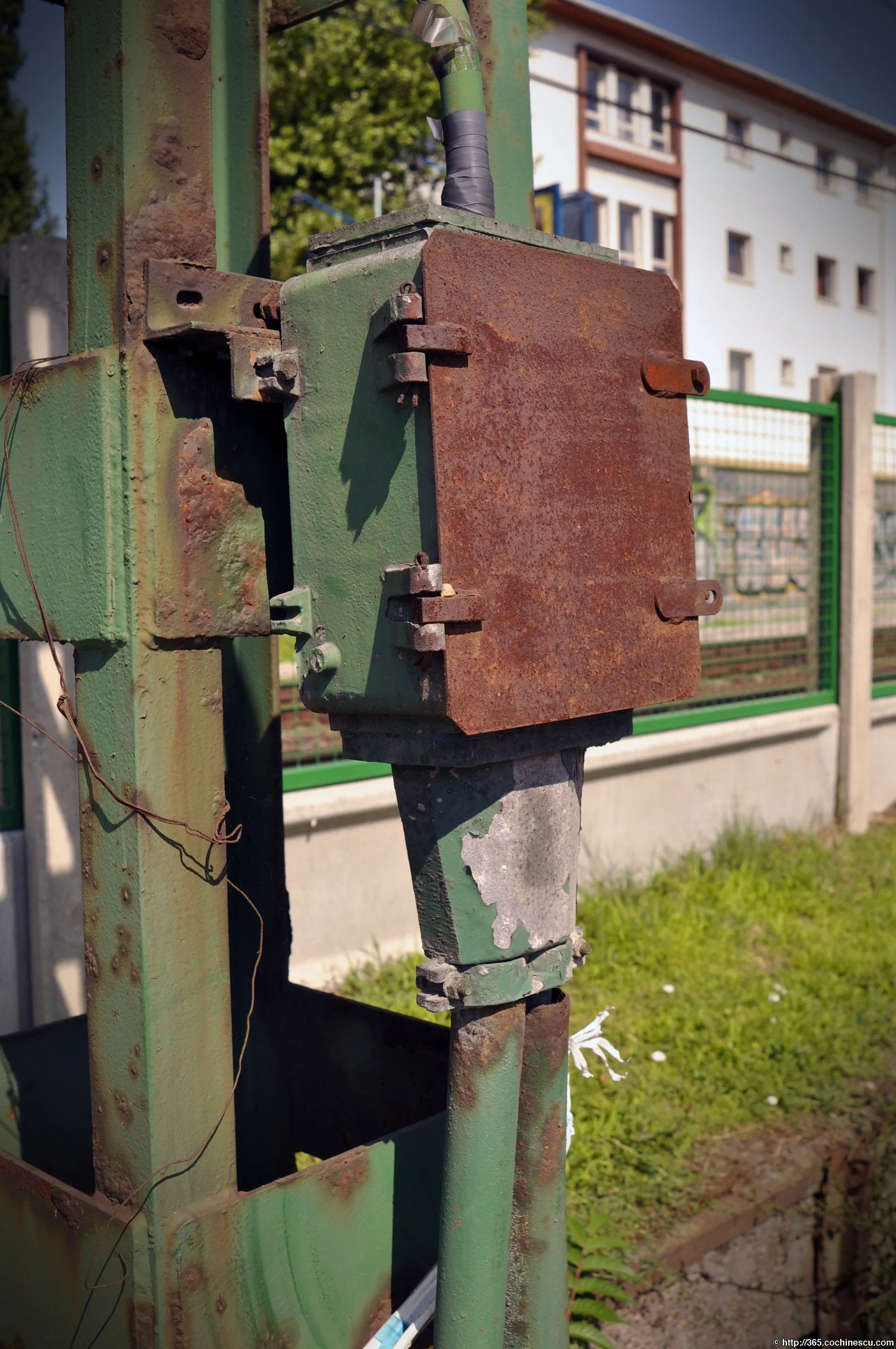 Un mecanism electric ruginit este montat pe un stâlp metalic verde din Budapesta.