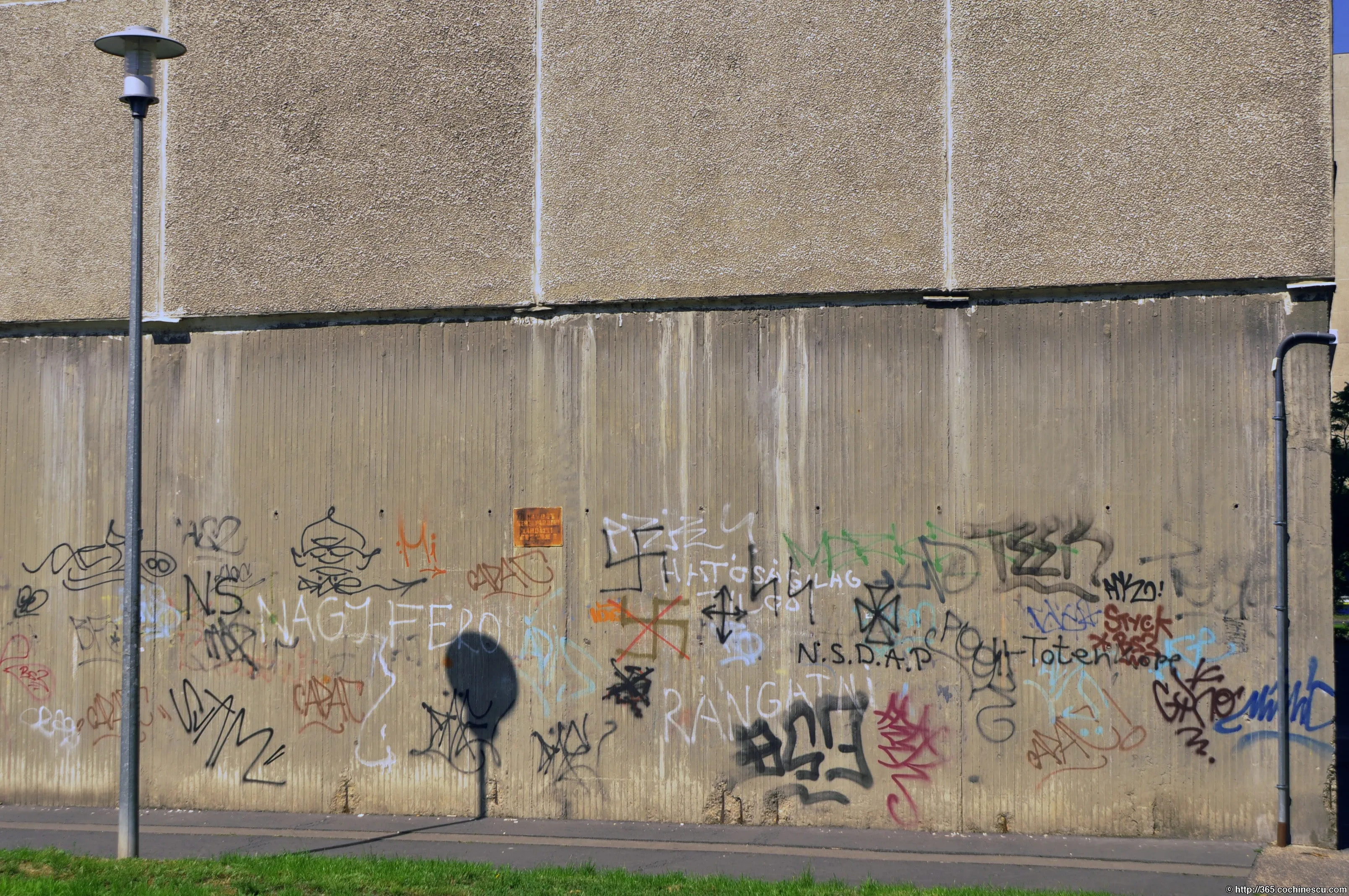 Un zid lung din beton este acoperit cu graffiti colorate.