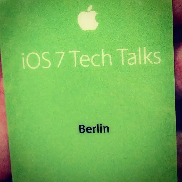 O insignă Apple verde, pe care scrie iOS 7 Tech Talks Berlin, este ținută între degete.