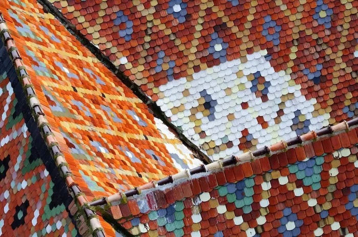 Un acoperiș este acoperit cu țigle smălțuite multicolore dispuse în modele geometrice.