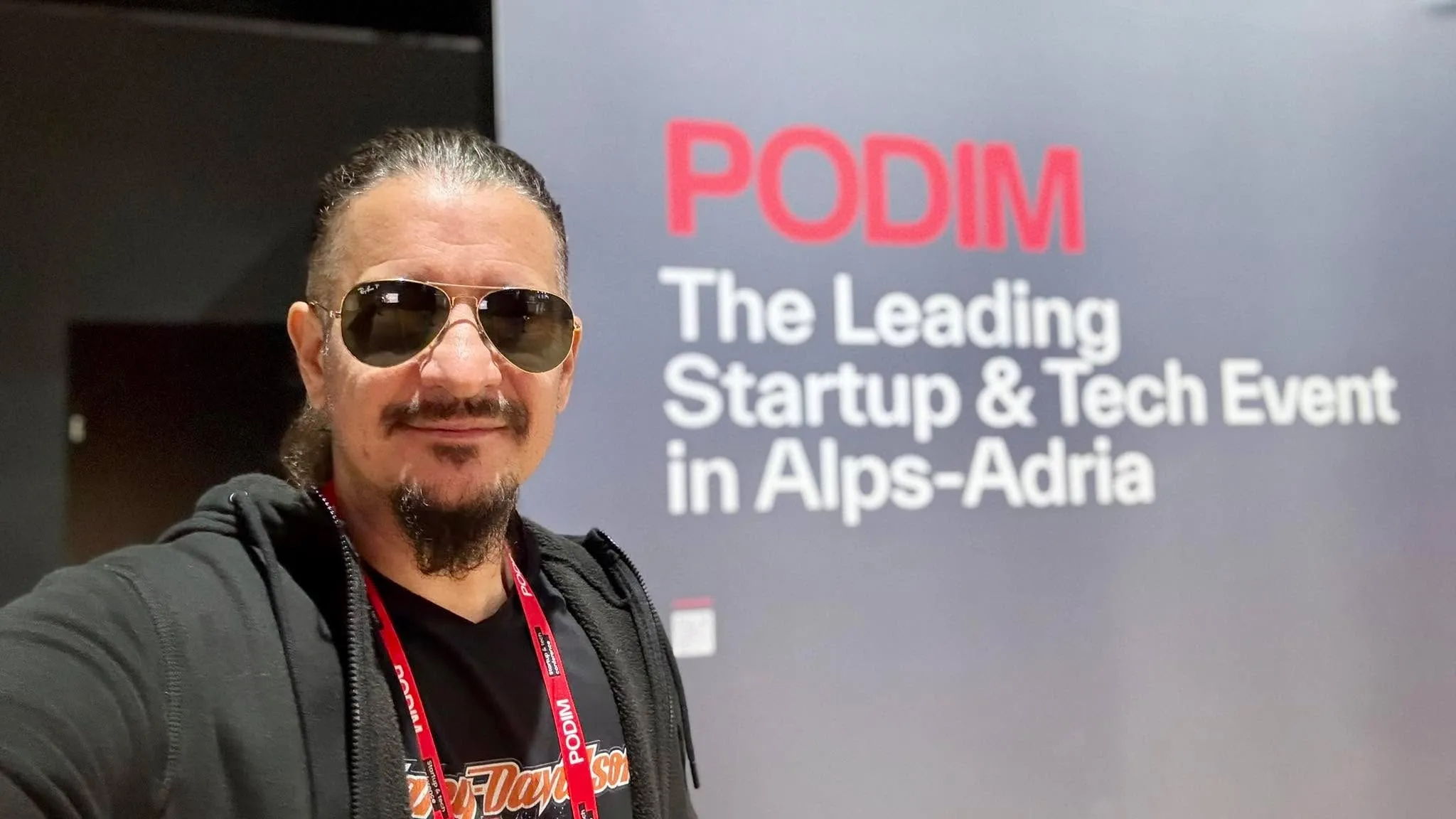 Sebastian Cochinescu își face un selfie în fața unui panou de la evenimentul Podim dedicat startupurilor și tehnologiei.